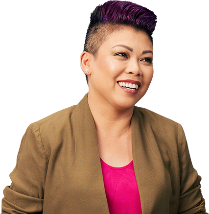 woman with short pink hair wearing brown blazer smiling. 