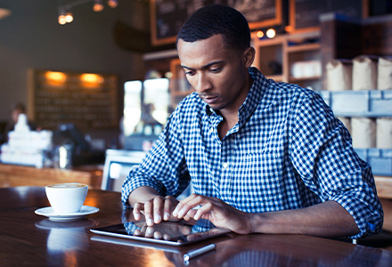 Man at coffee shop using tablet. 