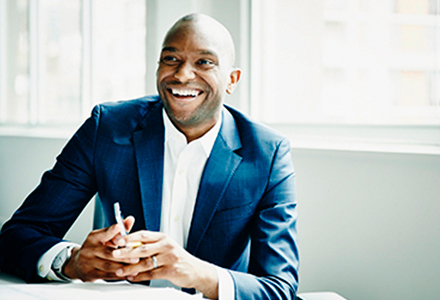Man in a suit holding a phone and smiling. 