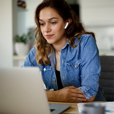 Young woman with bluetooth headphones having video conference at home.
