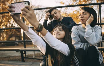 Three people taking a selfie with a cellphone. 