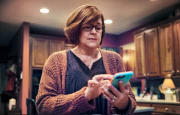 Woman using her cellphone in a kitchen. 