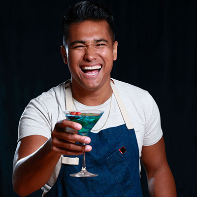 Chef and TV personality Jordan Andino smiling holding an Allstate blue mocktail. 